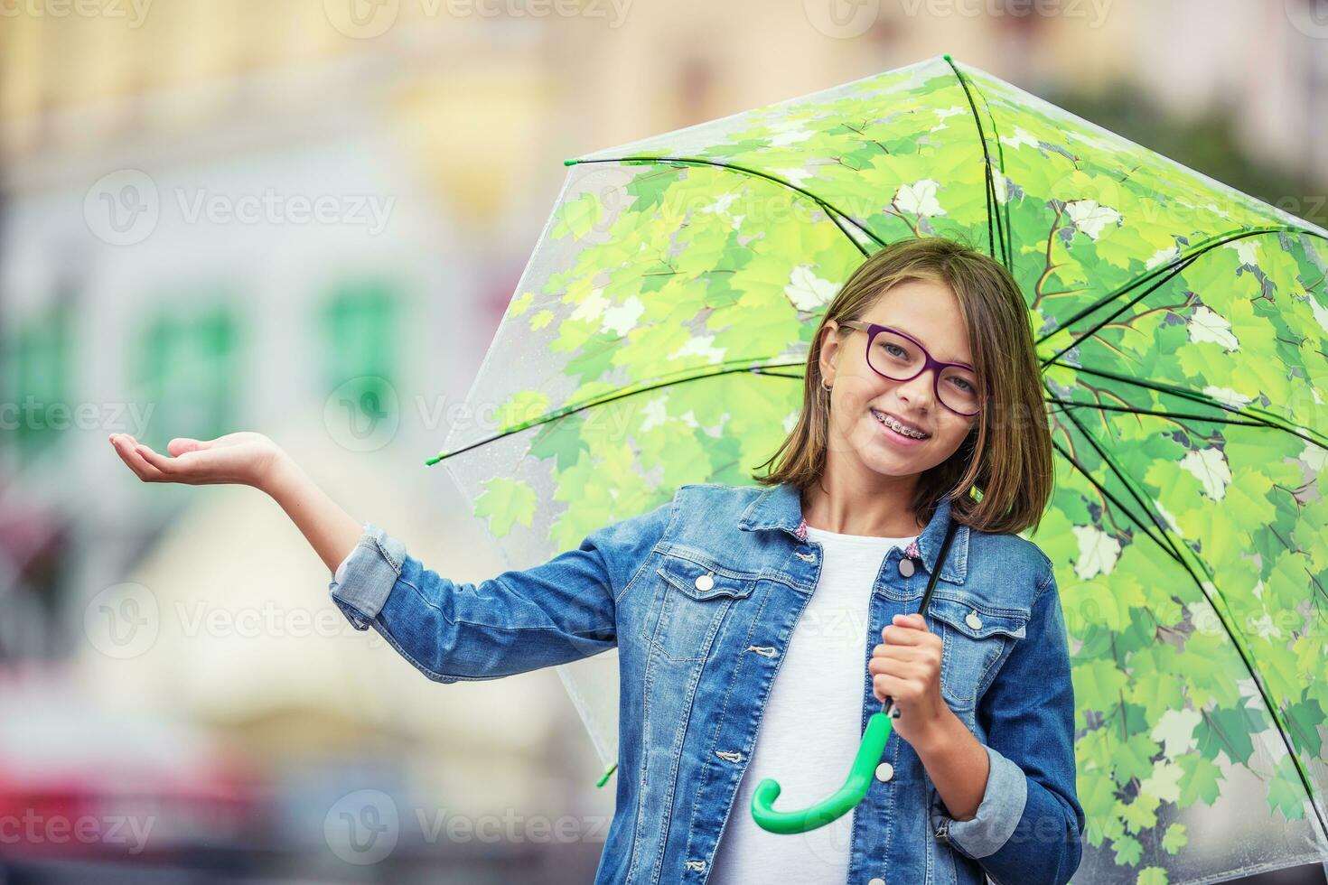 Portrait of beautiful young pre-teen girl with umbrella under rain photo