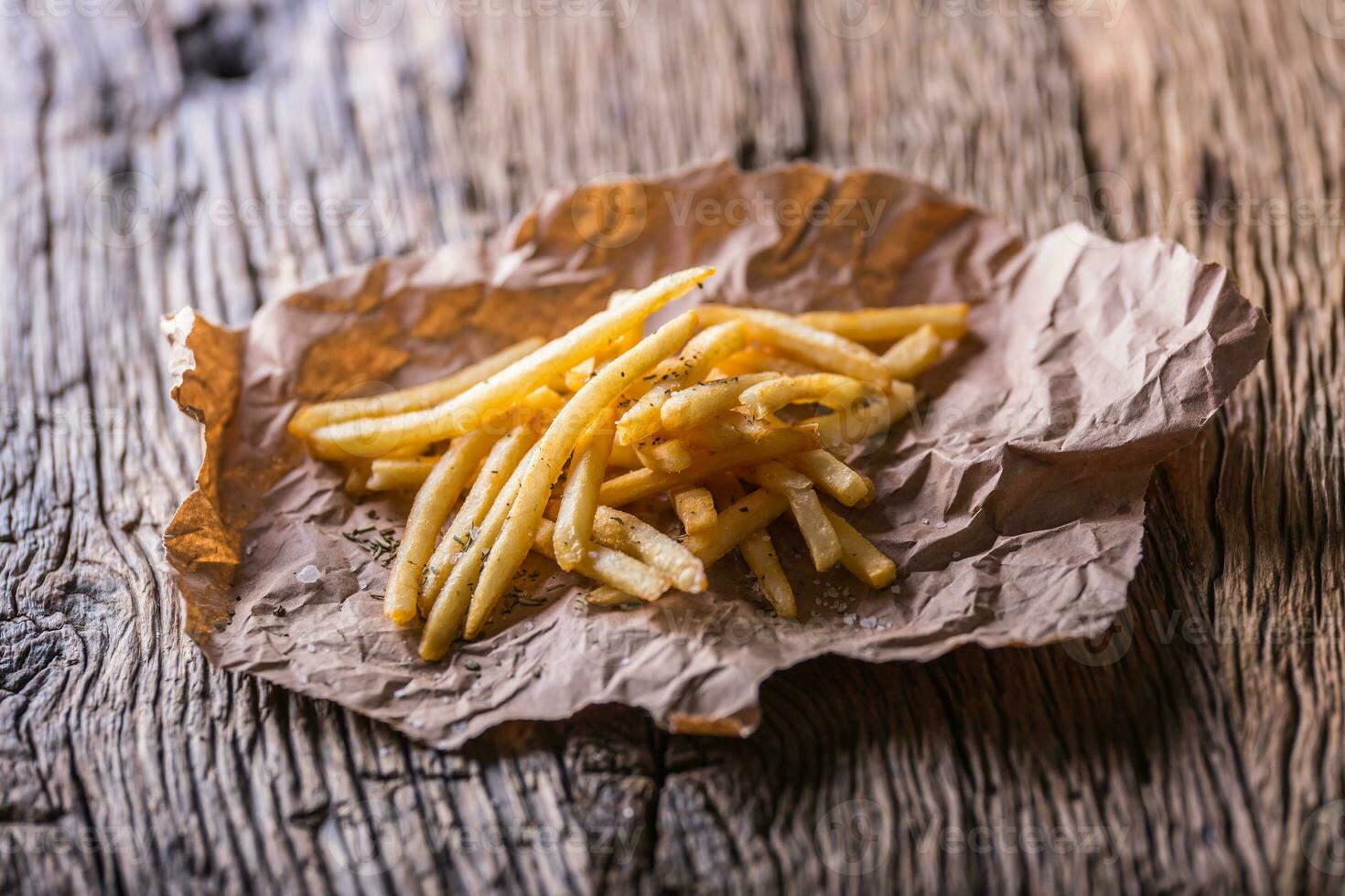Potato fries. Gold potato fries with salt and dry herbs on wooden board. photo