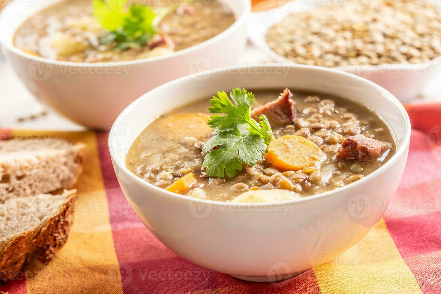 Lentil soup with pieces of smoked pork neck, carrots, potatoes and coriander photo