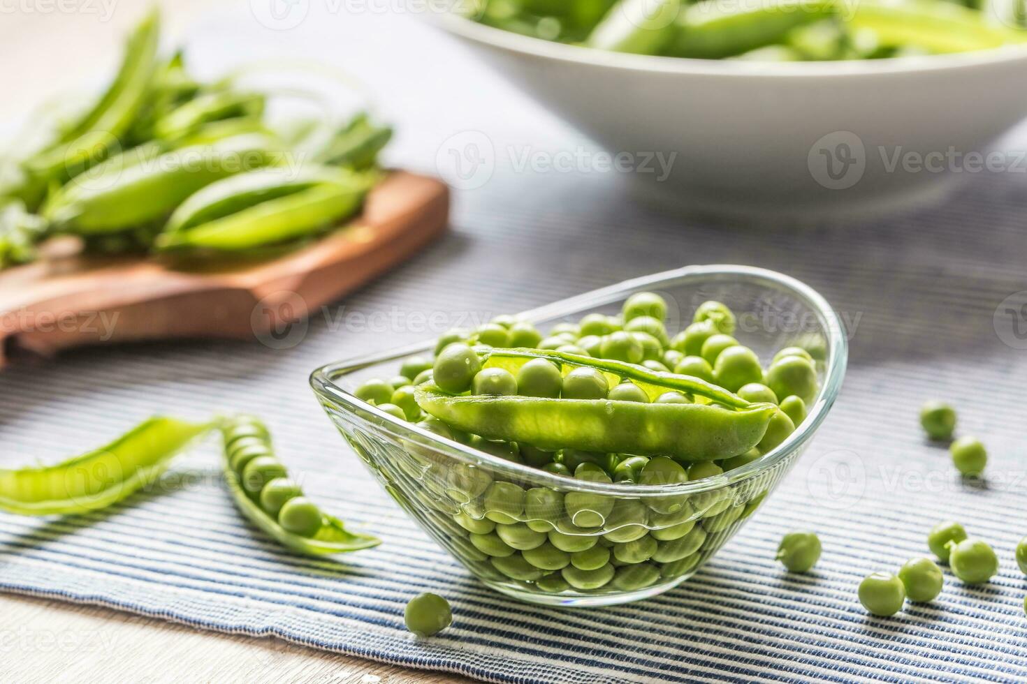 Fresh green pea seeds in bowl on kitchen table photo