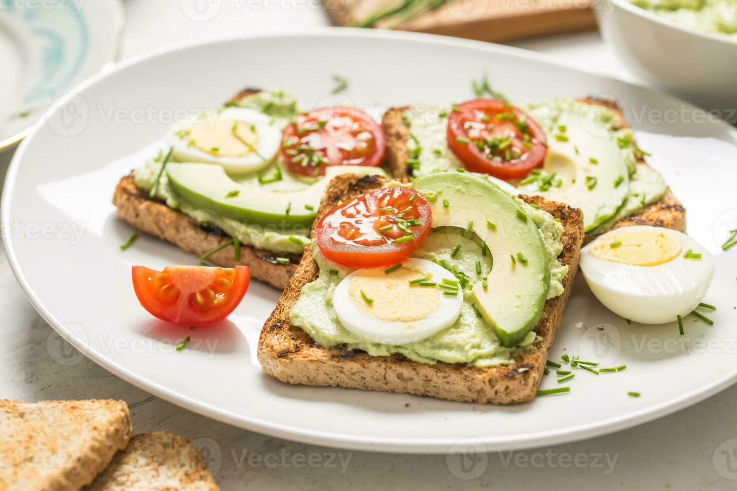 Healthy breakfast from toasts with avocado spread guacamole egg tomato and chives. photo