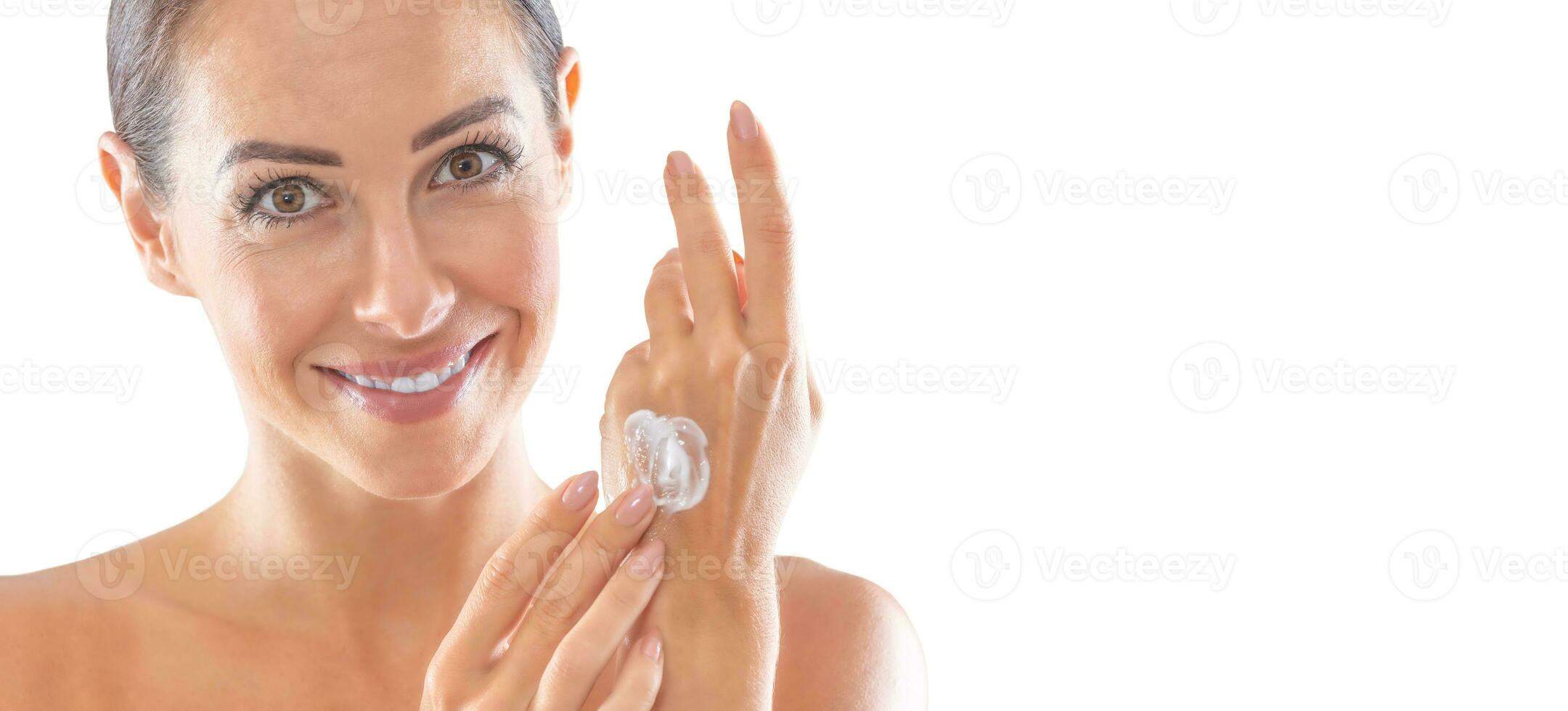 Beautiful young woman applying cream to her hand isolated on white. Skincare spa wellness and cosmetics concept photo