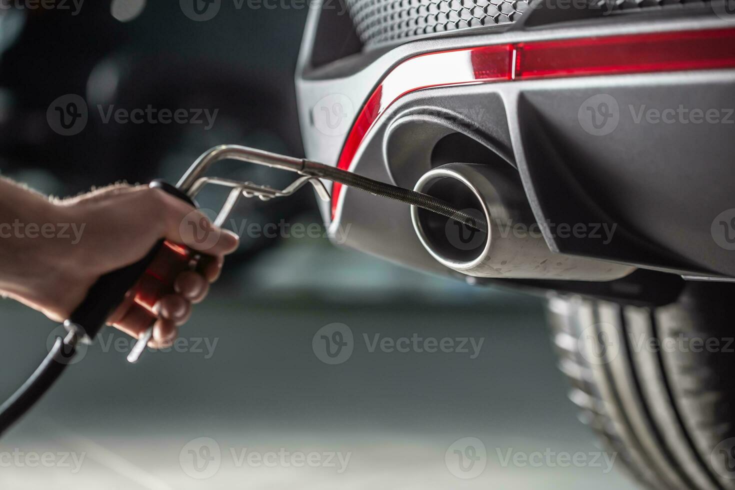 Measurement of exhaust emissions at the technical inspection station. A car repairman applies a probe to the exhaust photo