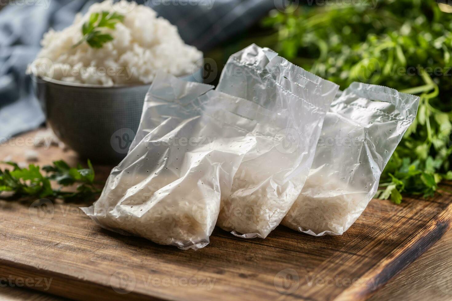 Raw rice in plastic bags on wooden background and cooked rice in bowl photo