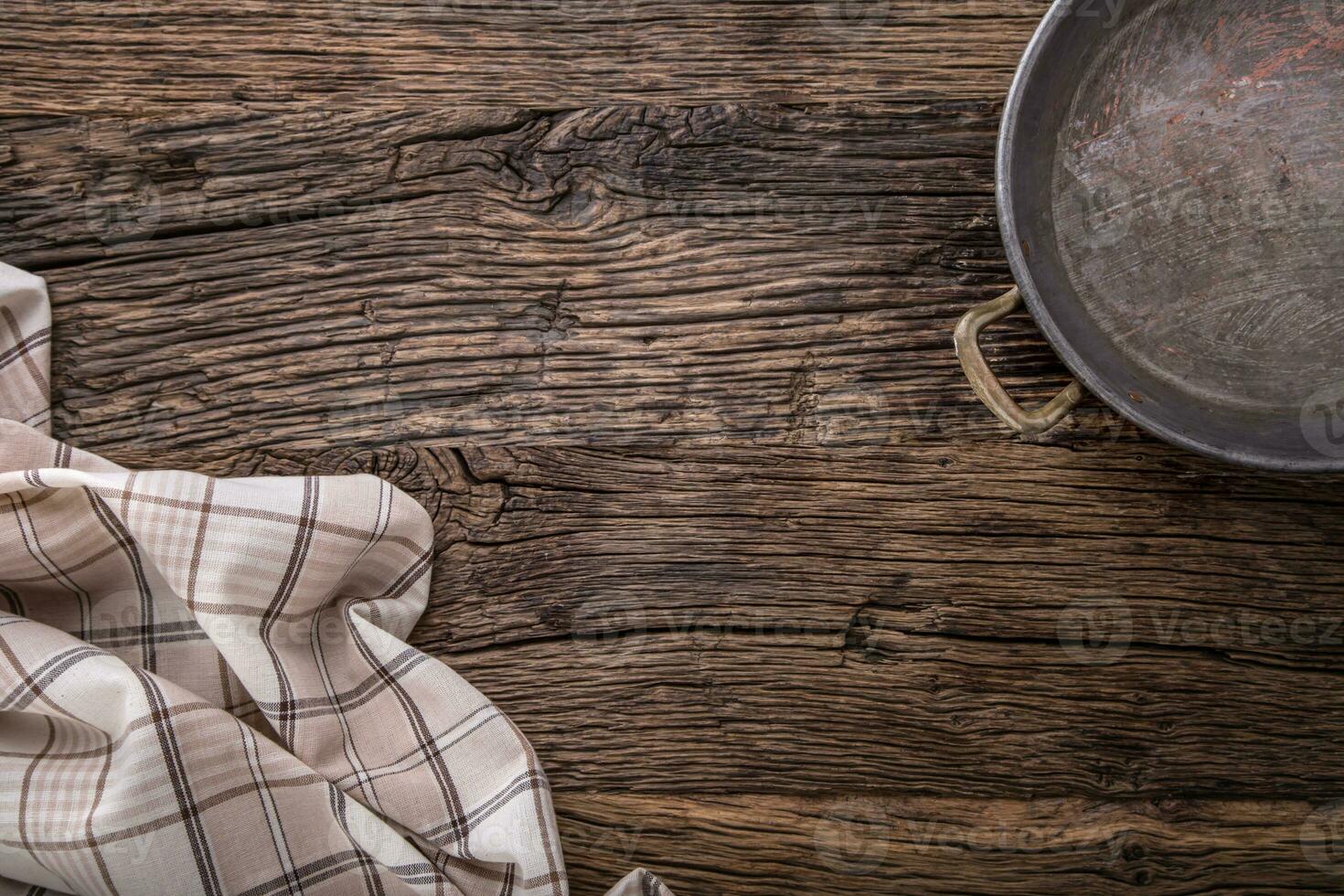 Top view of checkered tablecloth or napkin with pan on empty wooden table photo