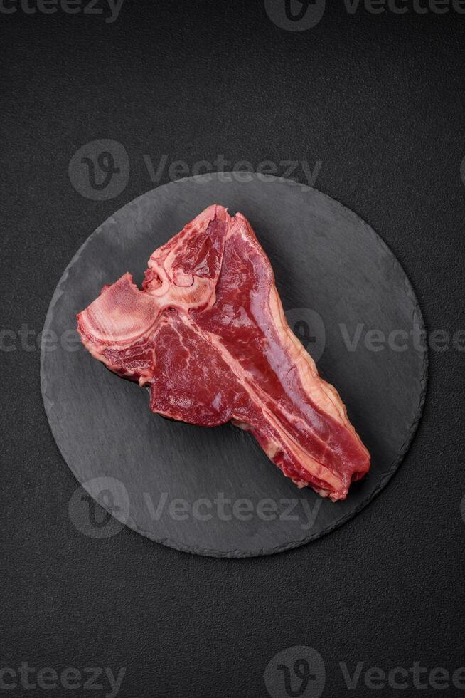 Raw fresh juicy beef t-bone steak with salt, spices and herbs photo