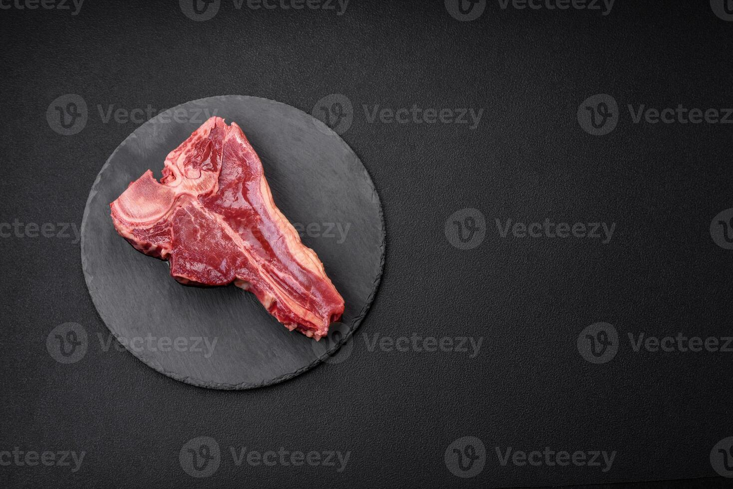 Raw fresh juicy beef t-bone steak with salt, spices and herbs photo