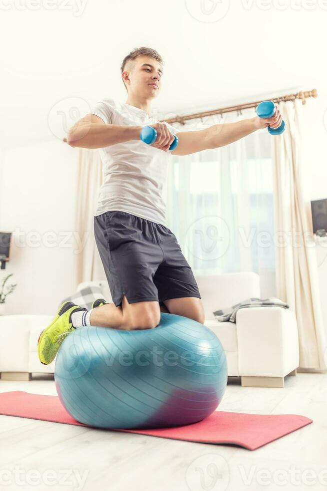 A young man exercises at home on a fitness ball photo