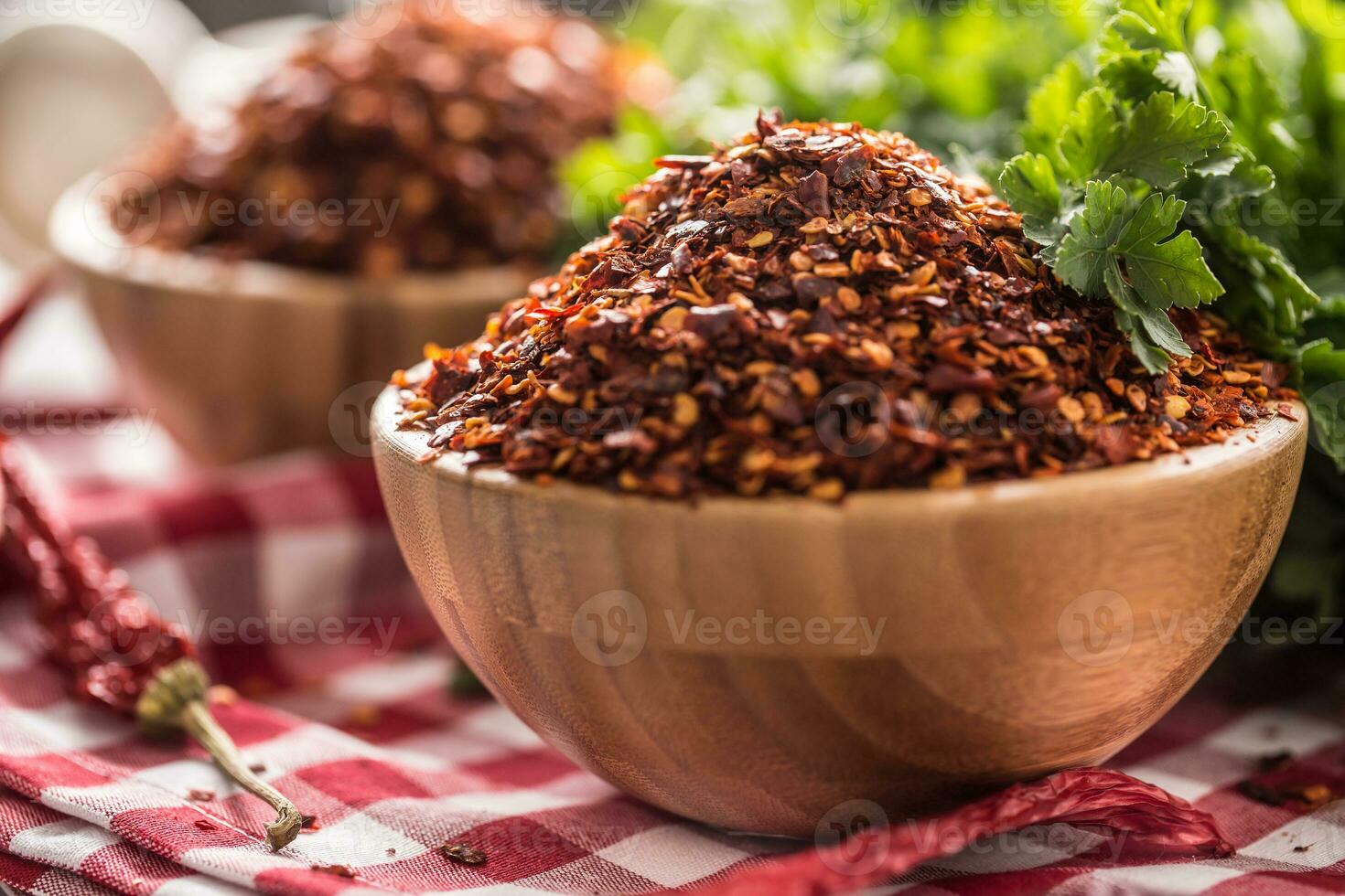 Dried and crushed chili peppers in wooden bowles with parsley herbs photo