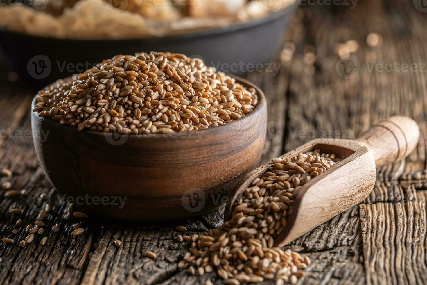 trigo granos-los principal ingrediente de el un pan lleno en de madera cuenco y de madera rústico cucharón. hornear crujiente un pan en el fondo foto