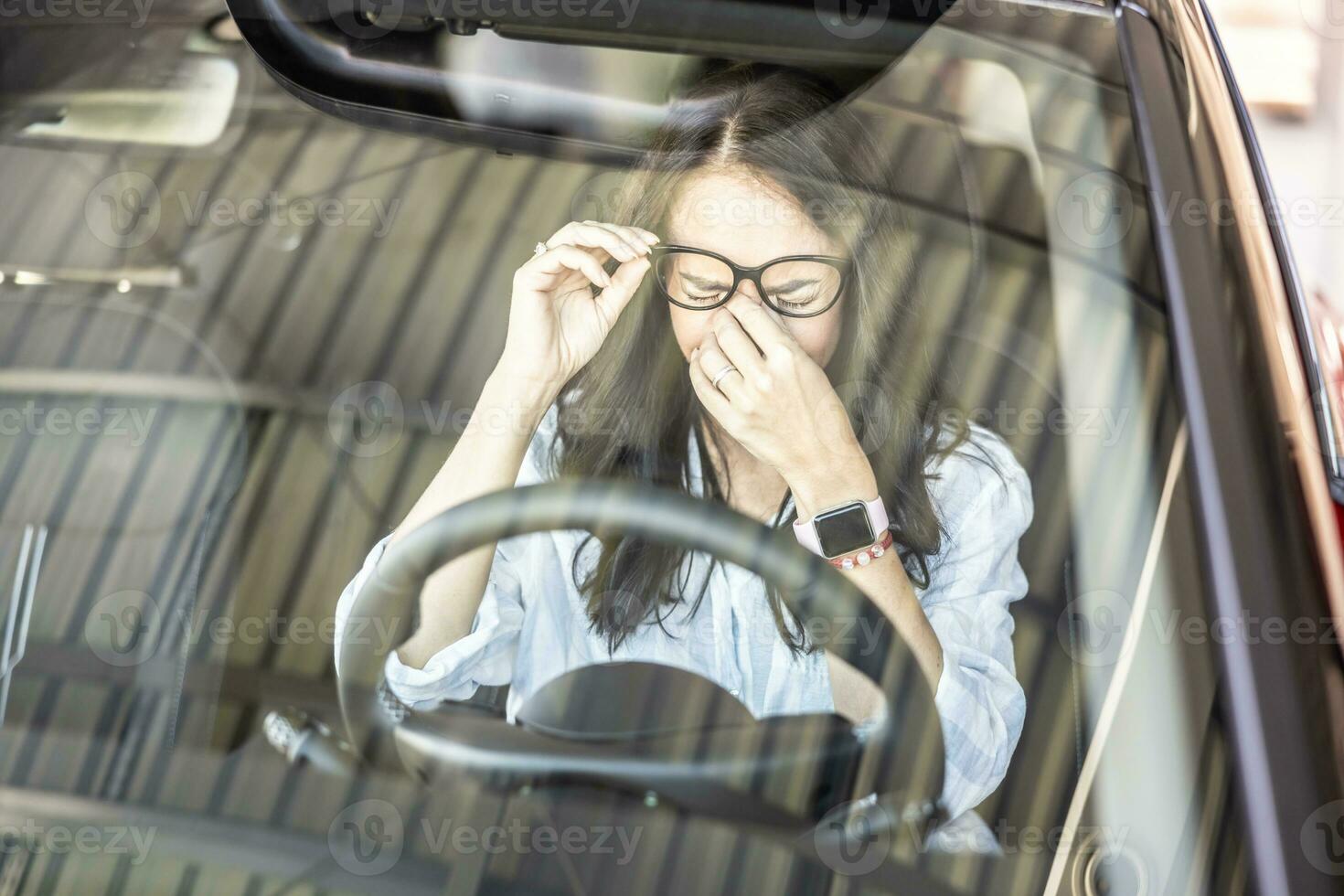Tired female driver with glasses, needs a break to continue driving the car photo