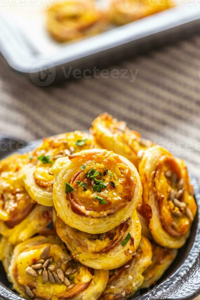 Rolls of puff pastry with ham bacon cheese sesame in dish photo