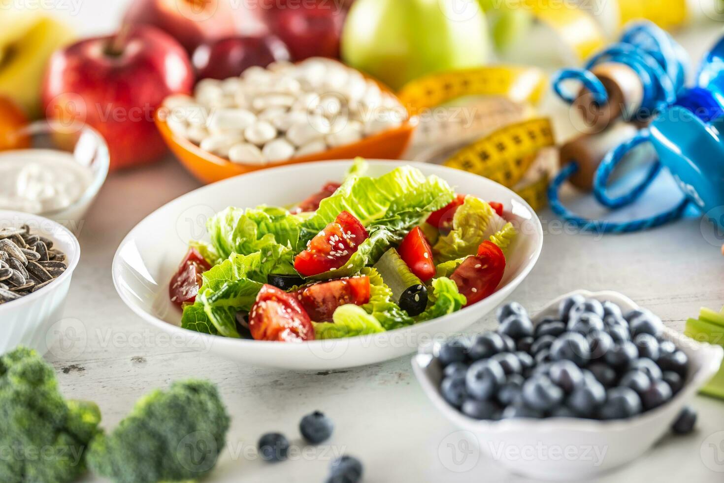 sano Fresco ensalada con Tomates aceitunas y aceituna aceite, rodeado por sano comida y ejercicio equipo foto