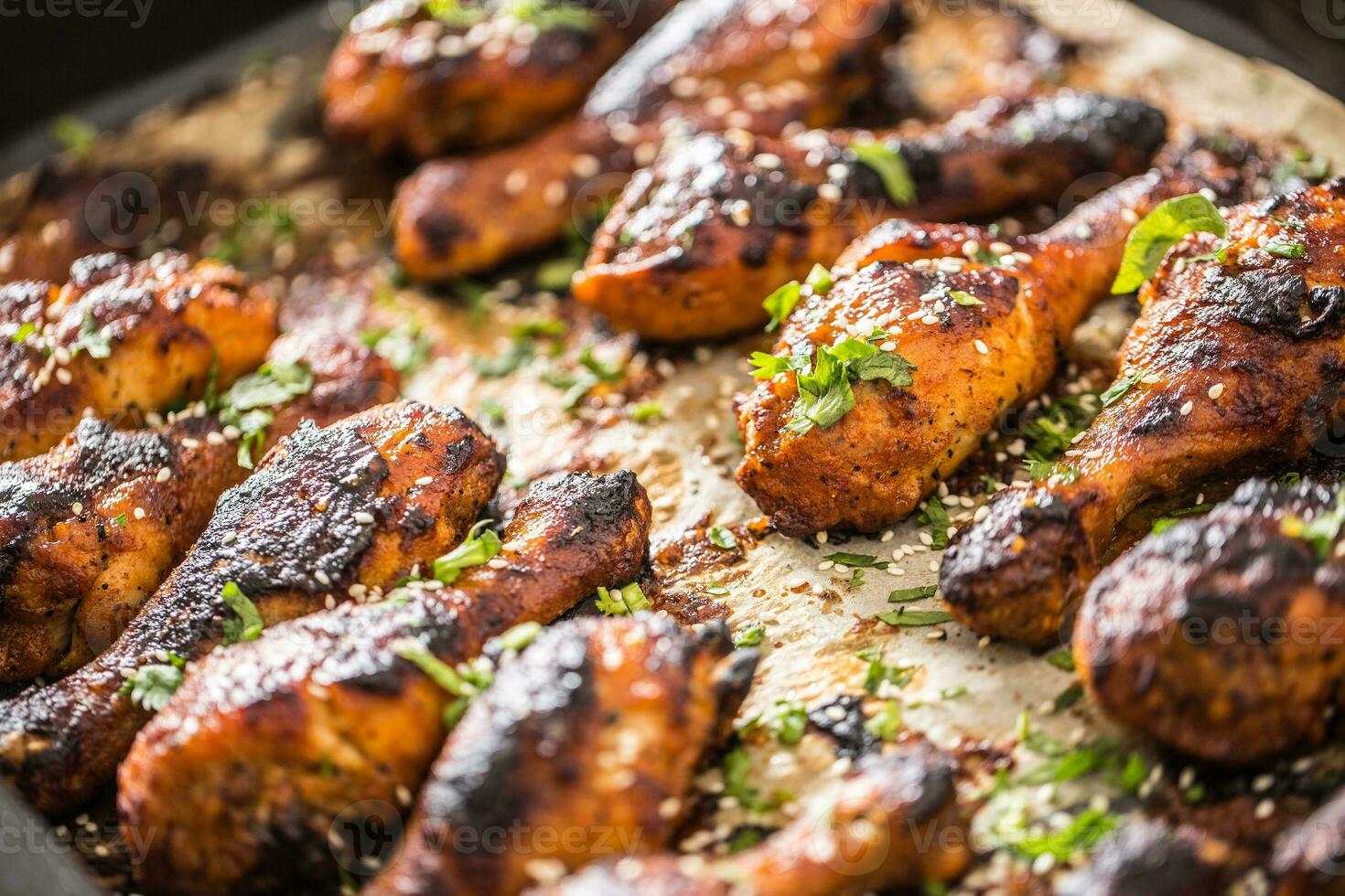 Grilled hicken legs BBQ with spices herbs and sesame on baked paper. Roasted poultry meal in roaster dish photo