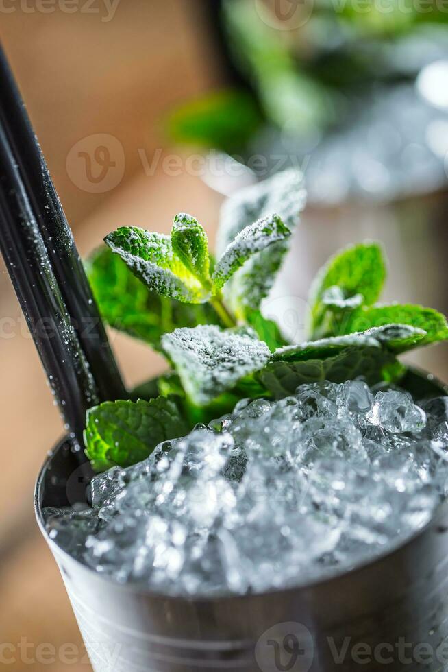 Mint julep cocktail alcoholic drink on wooden board in pub or restaurant photo