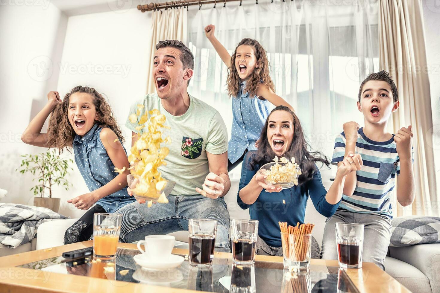 Raving fans cheering sports, as family of five watch football, or ice-hockey match on the TV at home, screaming from joy photo