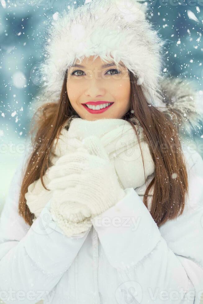 Beautiful smiling young woman in warm clothing. The concept of portrait in winter snowy weather photo