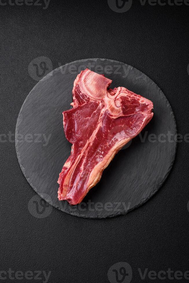 Raw fresh juicy beef t-bone steak with salt, spices and herbs photo