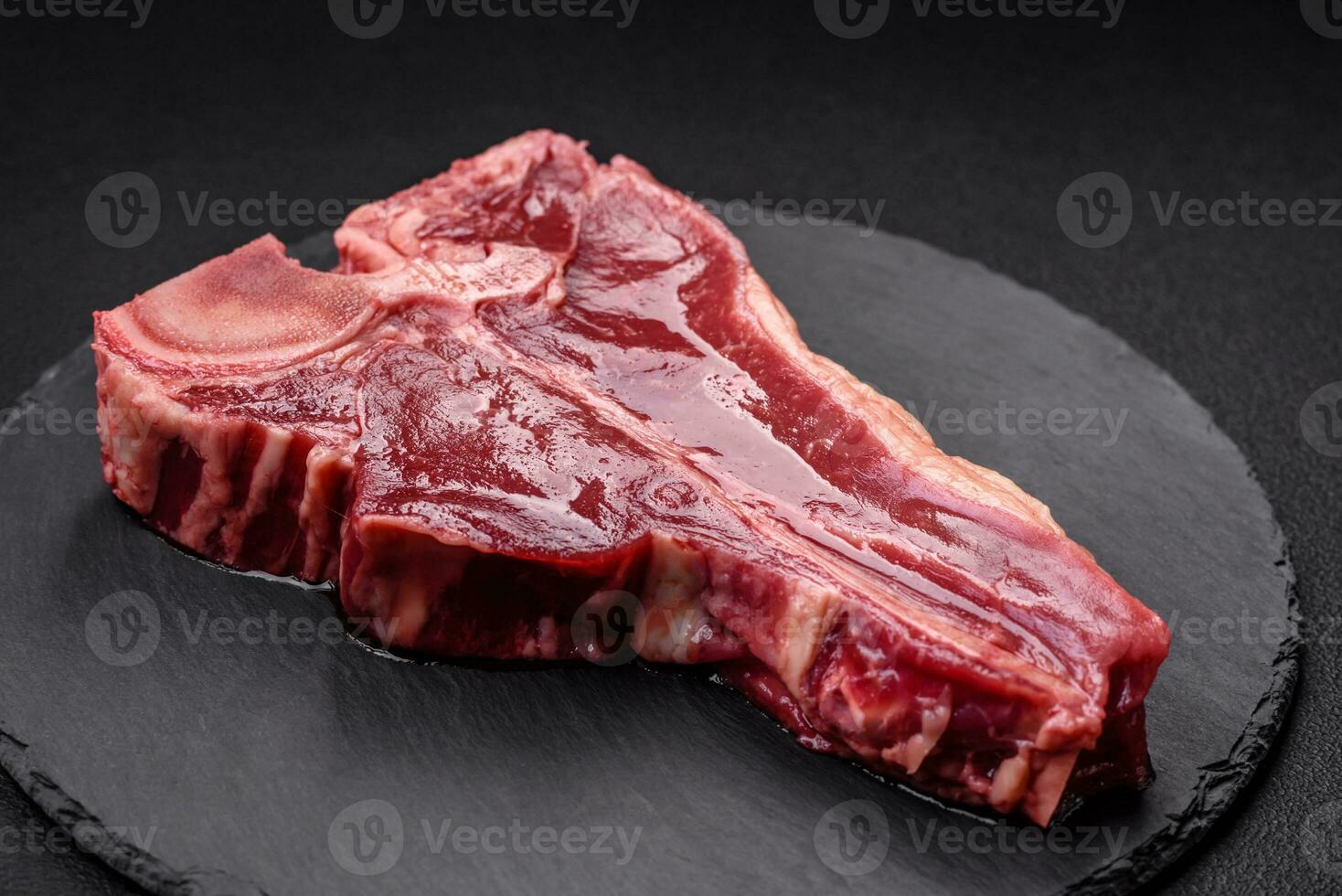 Raw fresh juicy beef t-bone steak with salt, spices and herbs photo