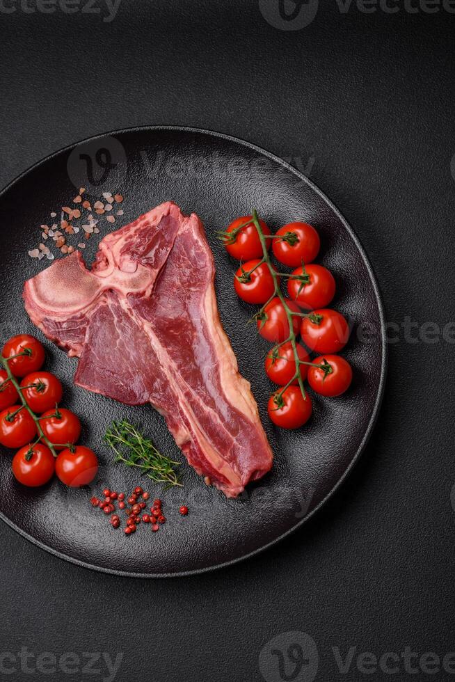 Raw fresh juicy beef t-bone steak with salt, spices and herbs photo