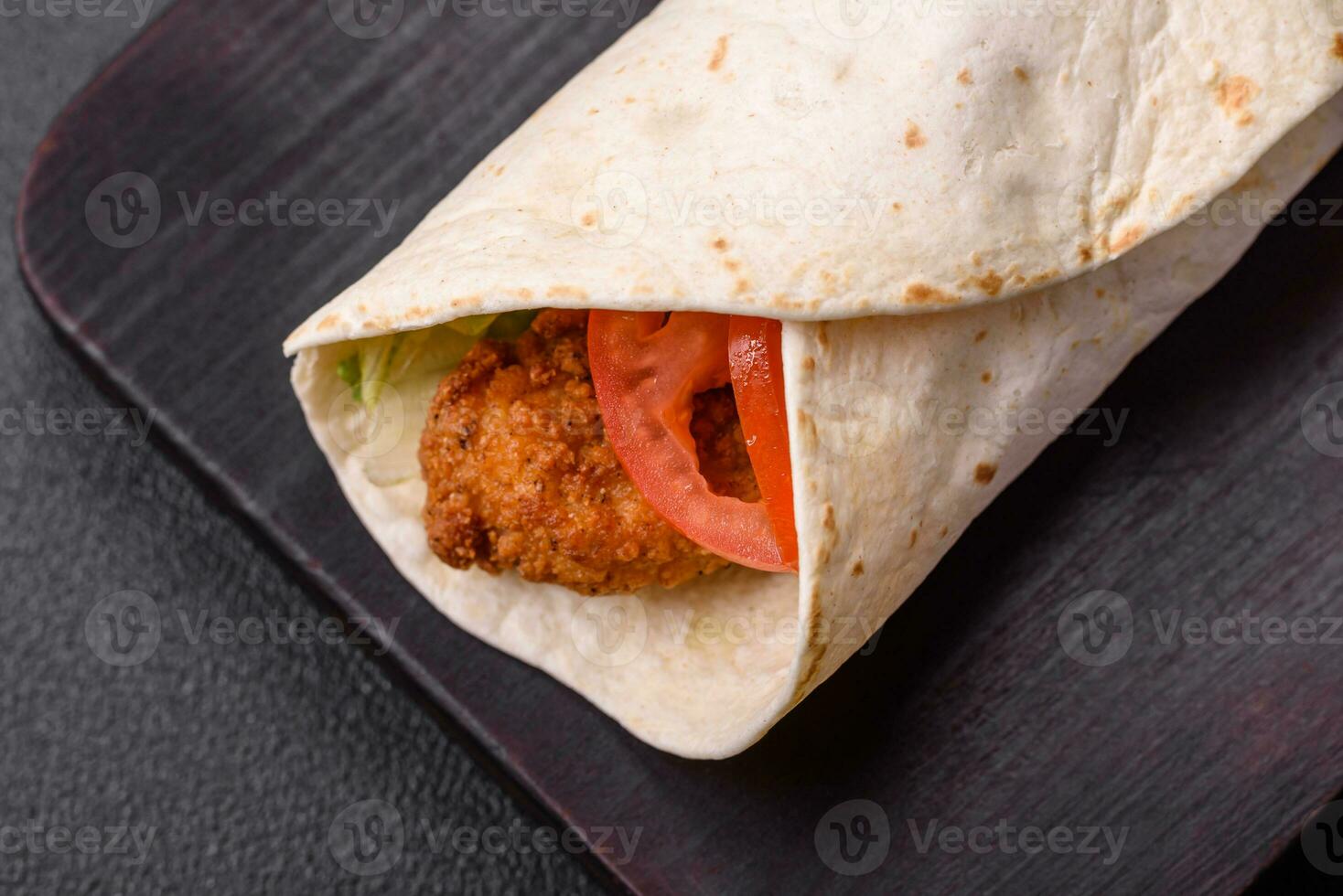 Delicious roll with chicken nuggets, tomatoes, lettuce and sauces with salt and spices photo