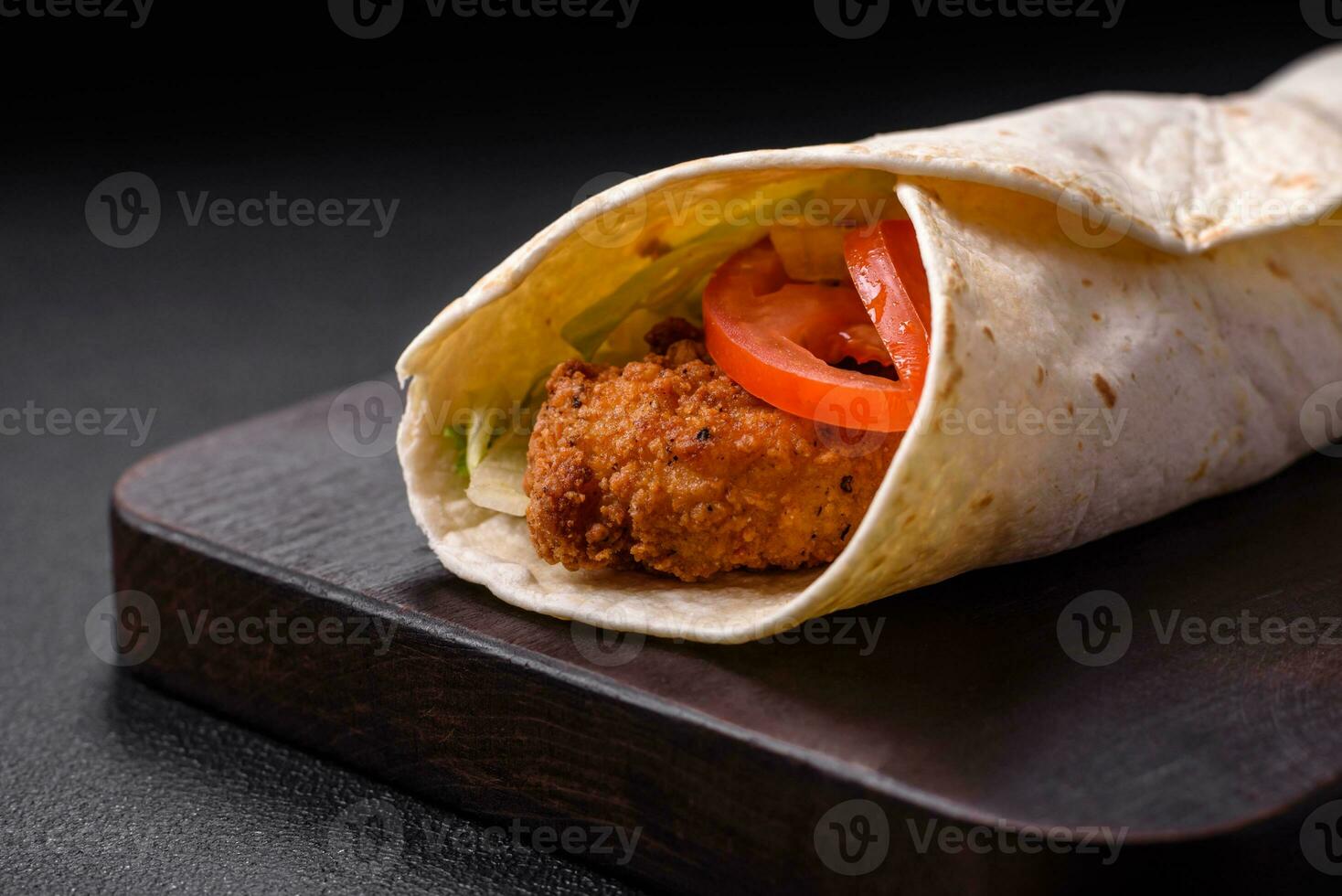 Delicious roll with chicken nuggets, tomatoes, lettuce and sauces with salt and spices photo