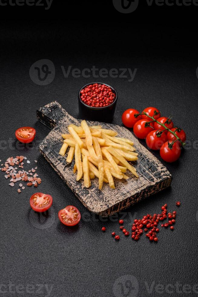 Delicious crispy french fries with salt and spices on a textured concrete background photo