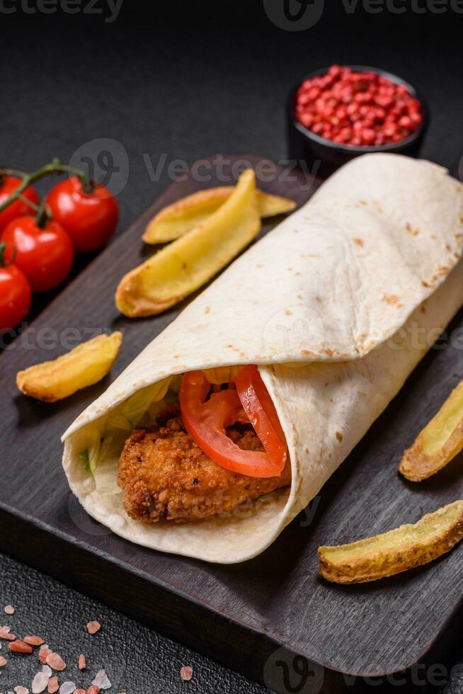 Delicious roll with chicken nuggets, tomatoes, lettuce and sauces with salt and spices photo