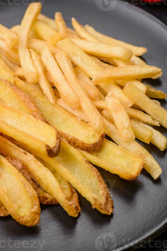 delicioso crujiente francés papas fritas con sal y especias en un texturizado hormigón antecedentes foto
