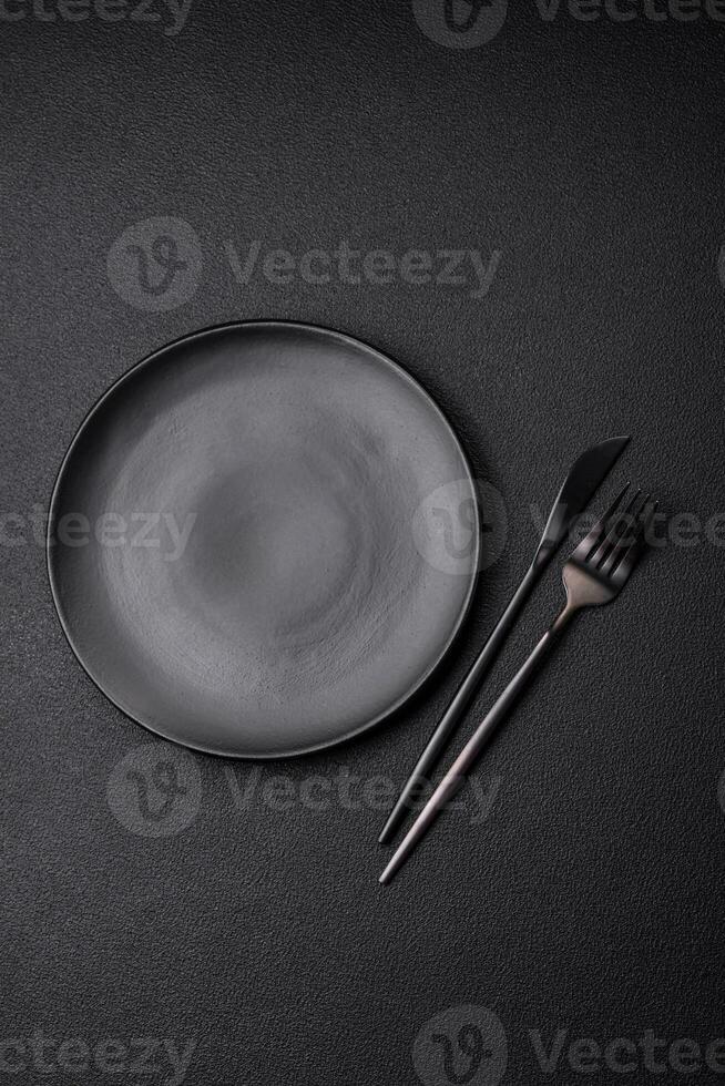 Empty black plate over dark stone background with copy space photo