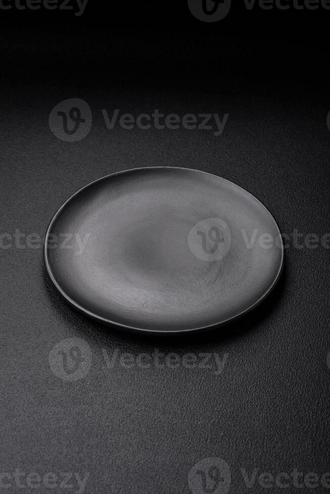 Empty black plate over dark stone background with copy space photo