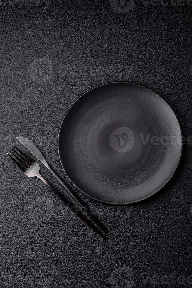 Empty black plate over dark stone background with copy space photo