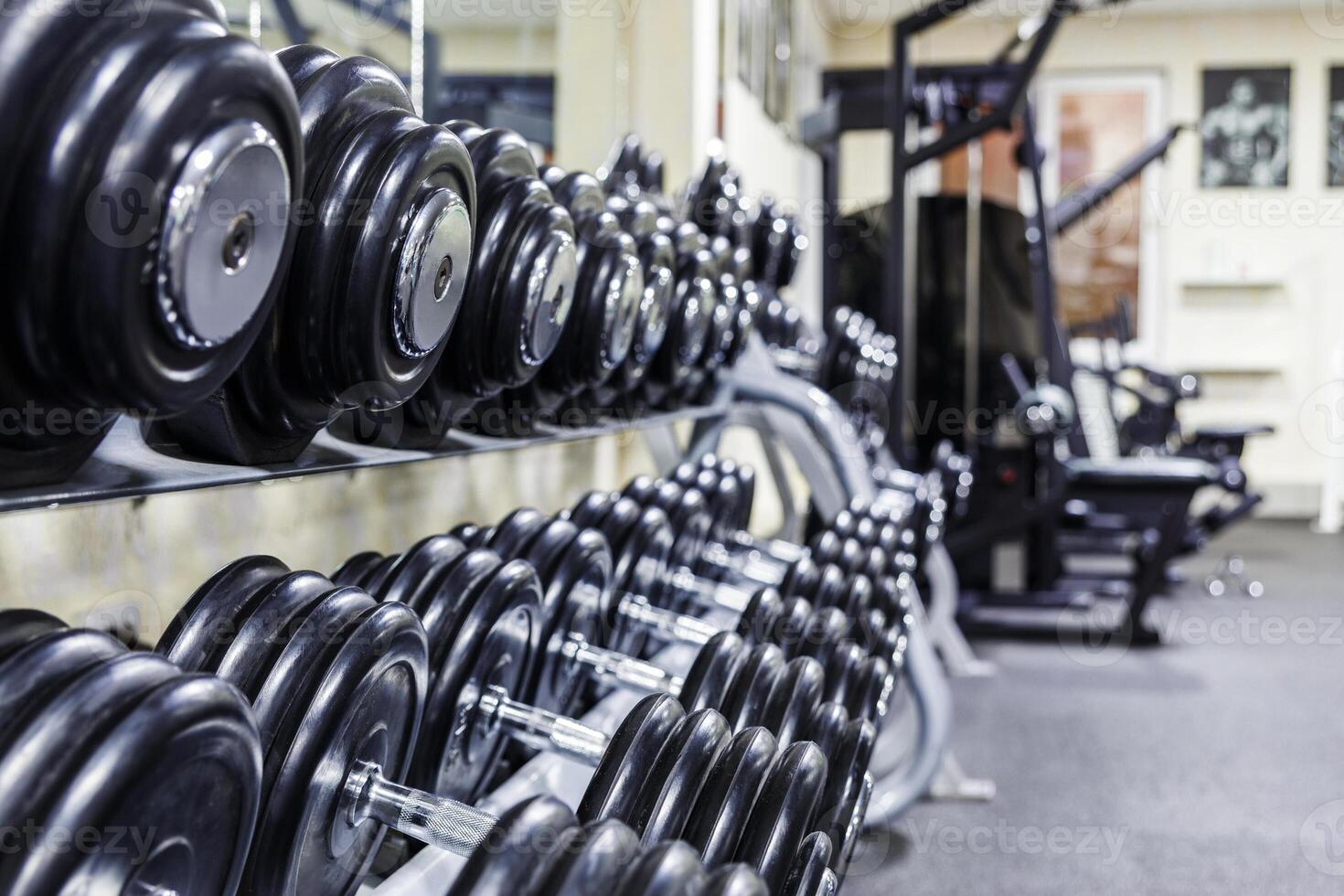 Black dumbbell set. Close up many rubberized dumbbells on rack in sport fitness center , Weight Training Equipment concept photo