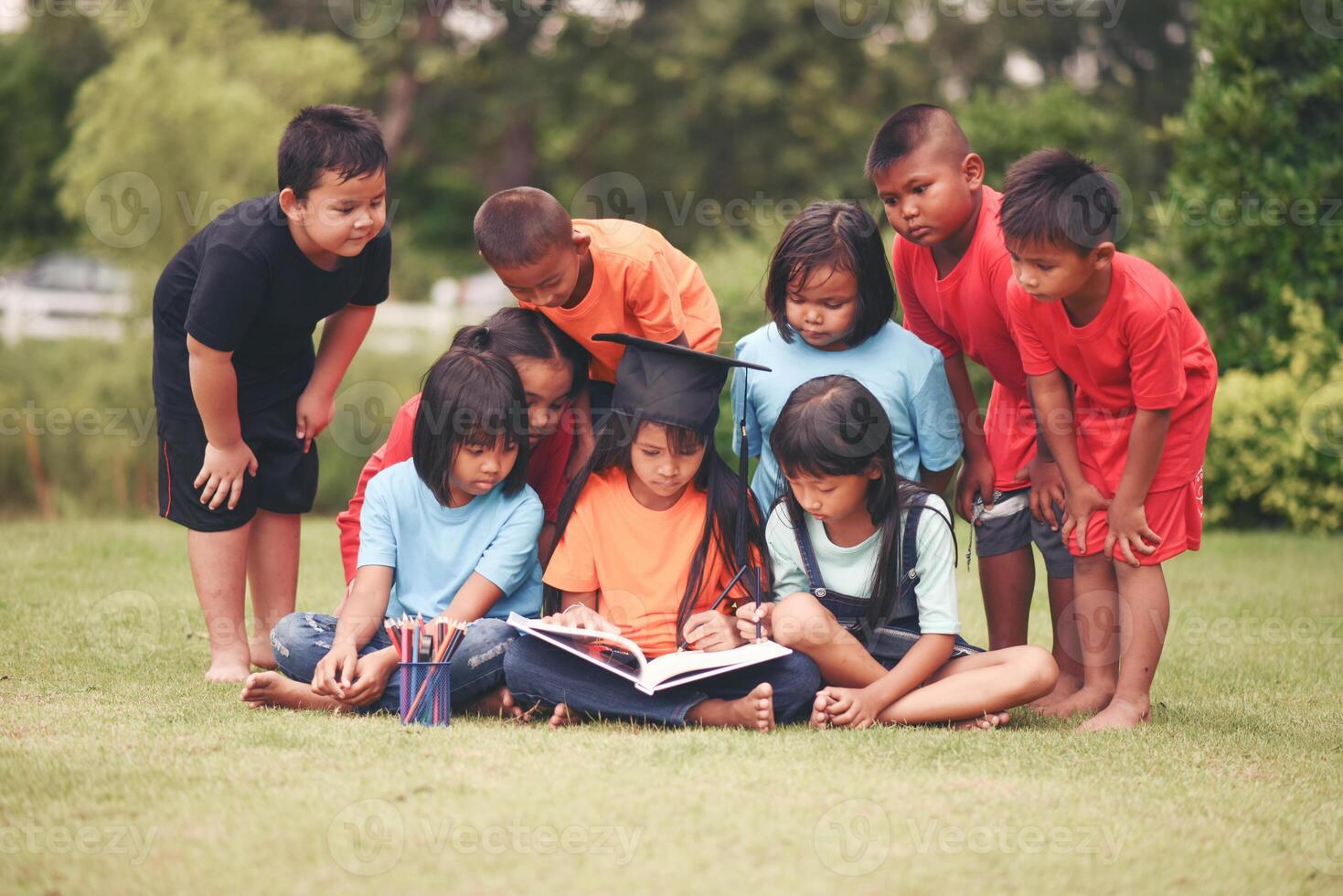 Group of children lying reading on grass field photo