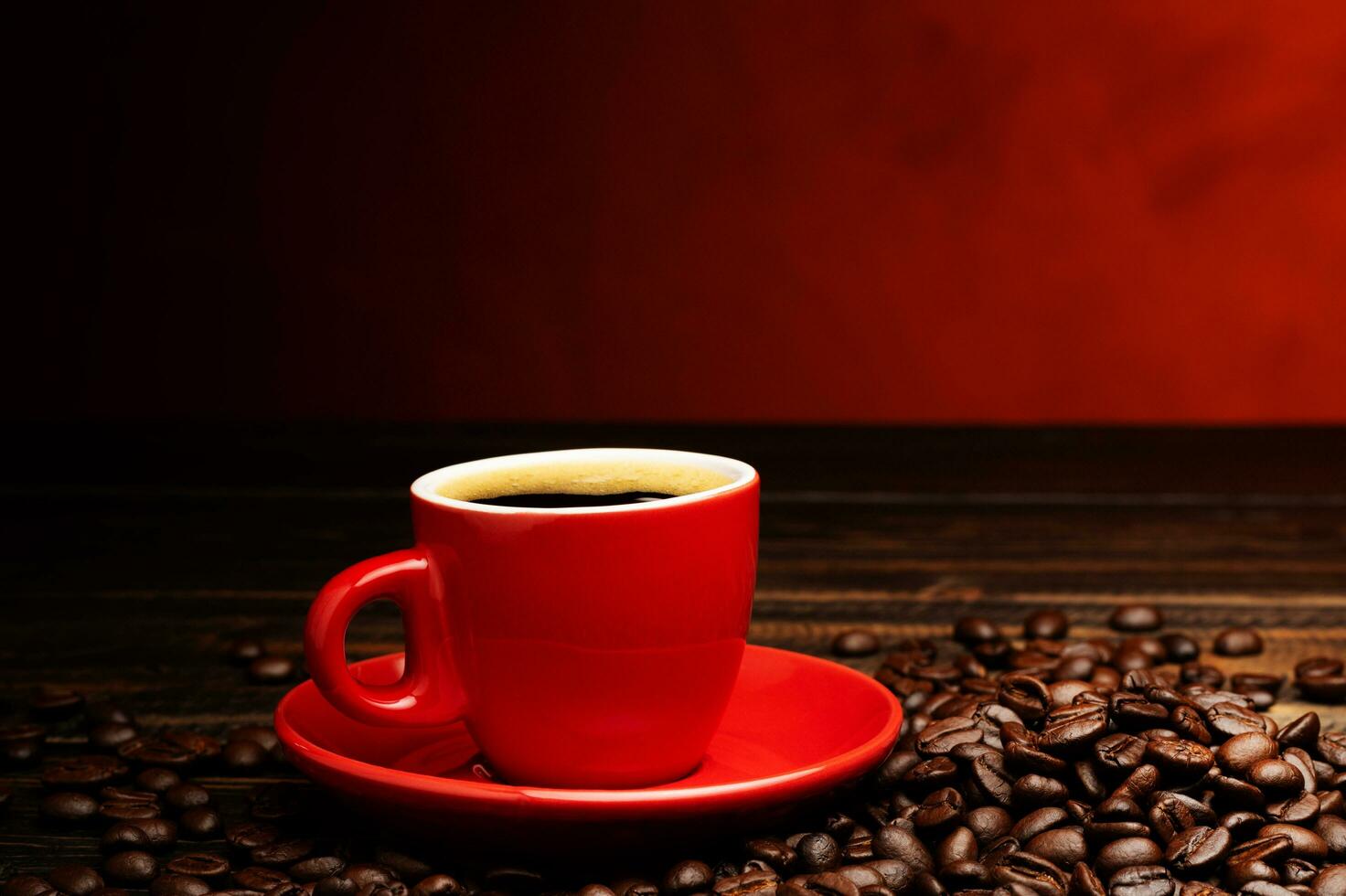 Black coffee or hot tea in a red coffee cup cappuccino espresso Breakfast with coffee beans on wooden table Isolated on black background. Top view. photo