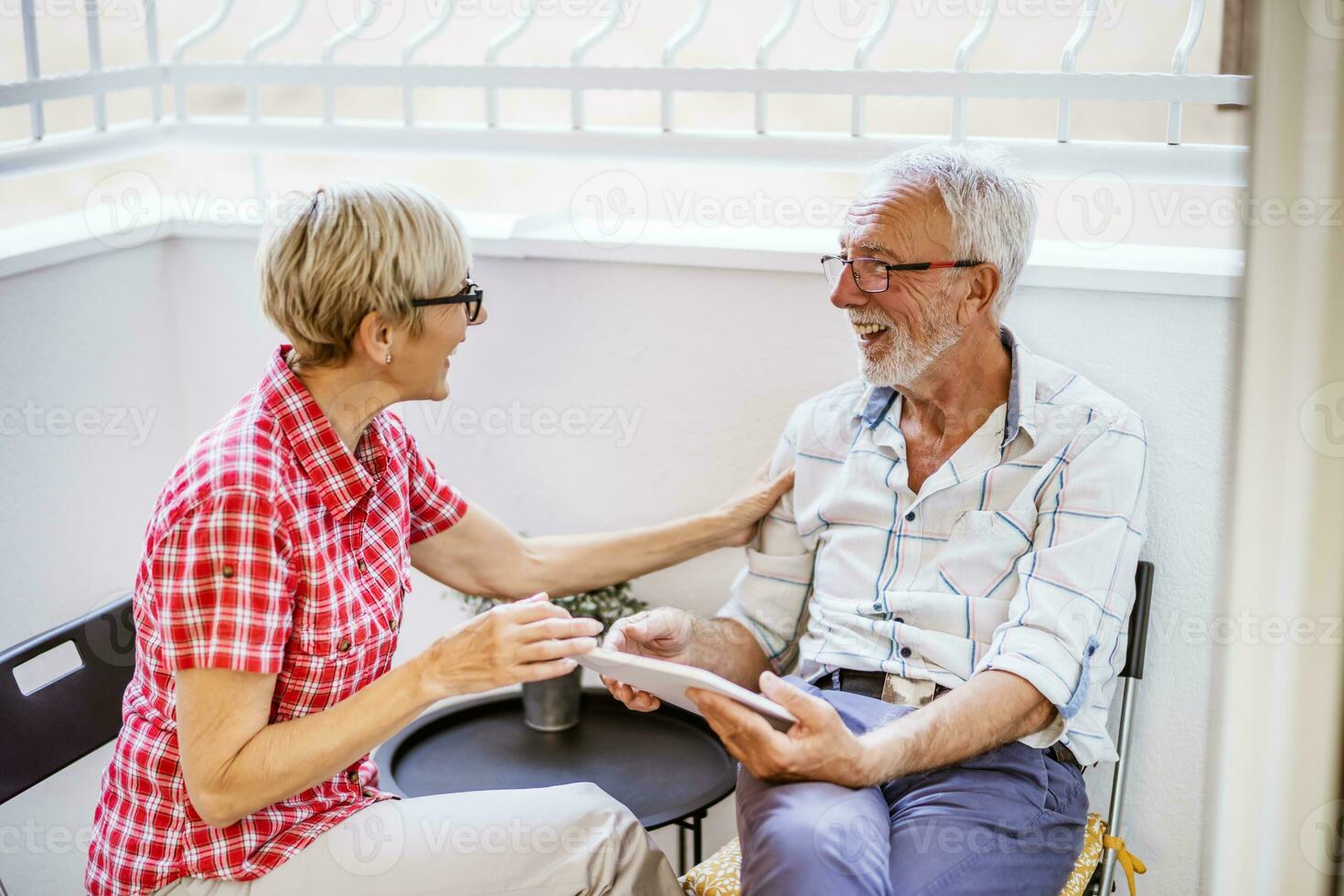 Senior couple sitting and talking on terrace at their home. Leisure time. photo