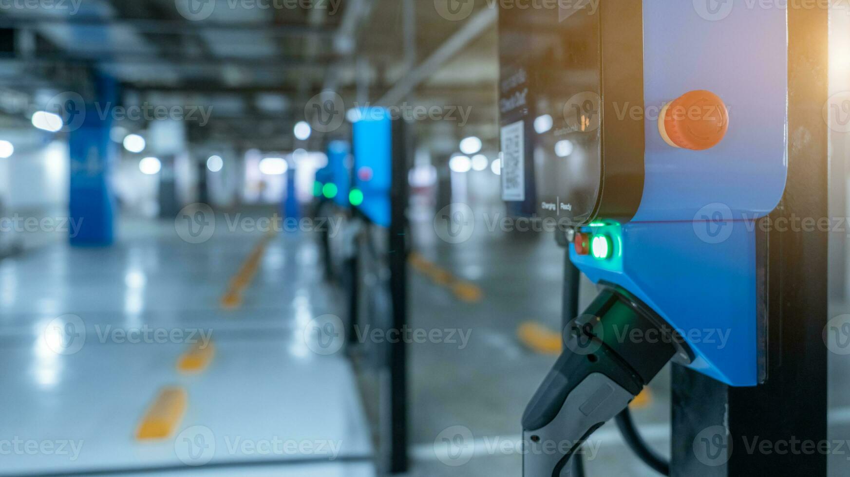 Blurred electric car charging station for charge EV battery. Plug for vehicle with electric engine. EV charger. Clean energy. Charging point at car parking lot. Future transport technology. photo