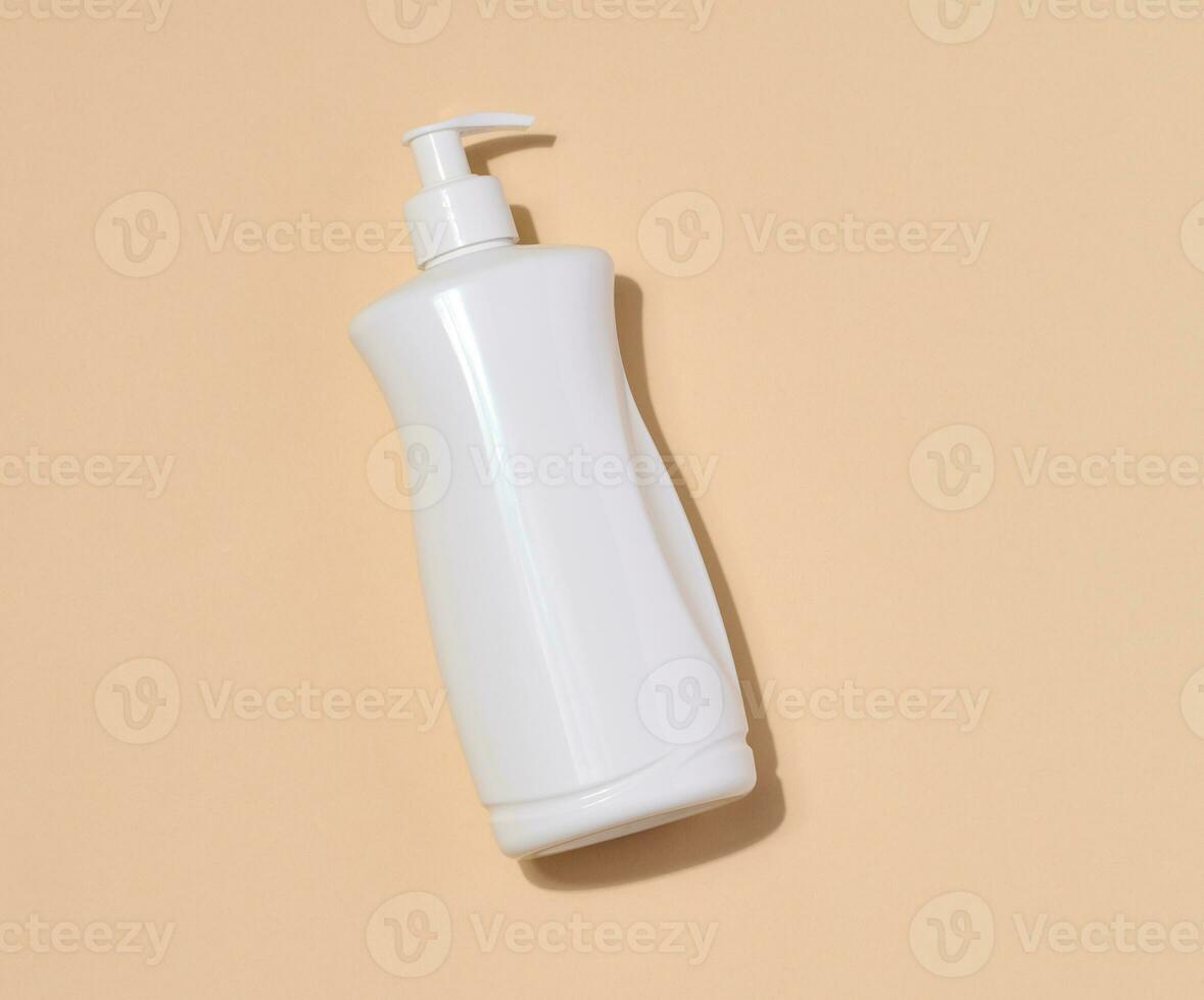 White plastic container with a pump for liquid products on a beige background. Container for cosmetics, soap, cream photo