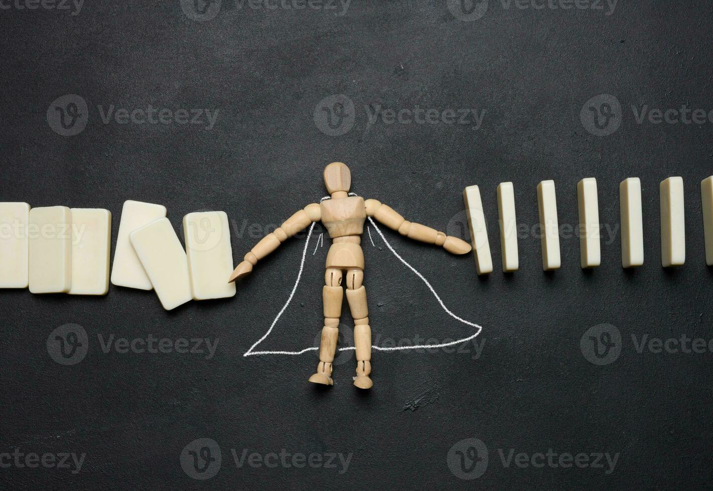 Wooden puppet toy holding a falling domino photo