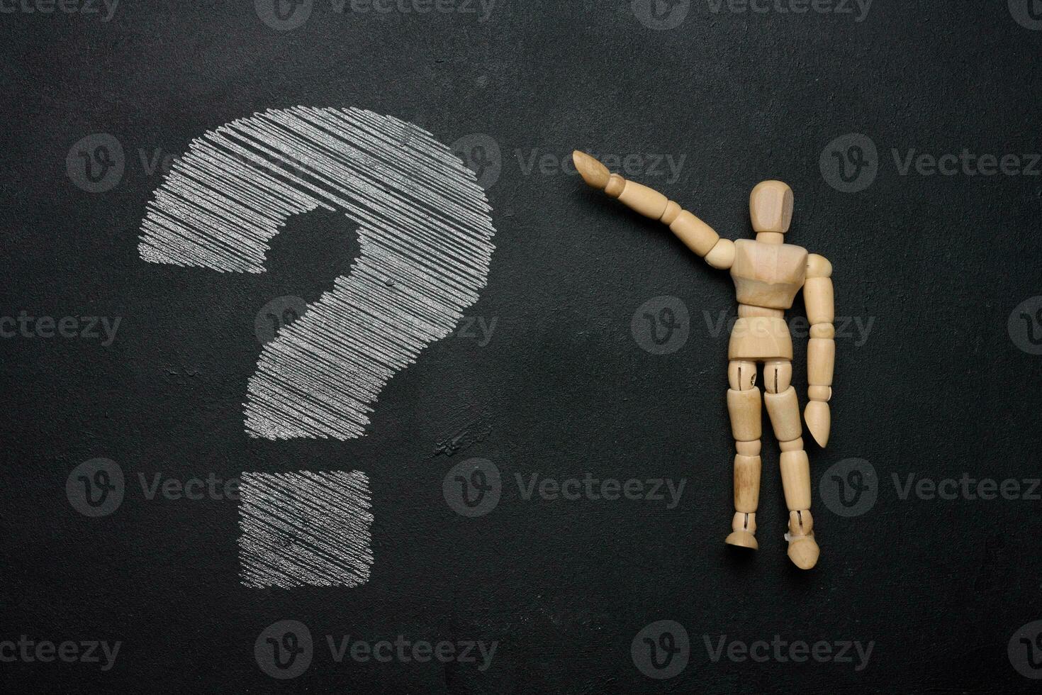 A wooden mannequin and a white chalk-drawn question mark on a black board, depicting the concept of uncertainty and curiosity photo