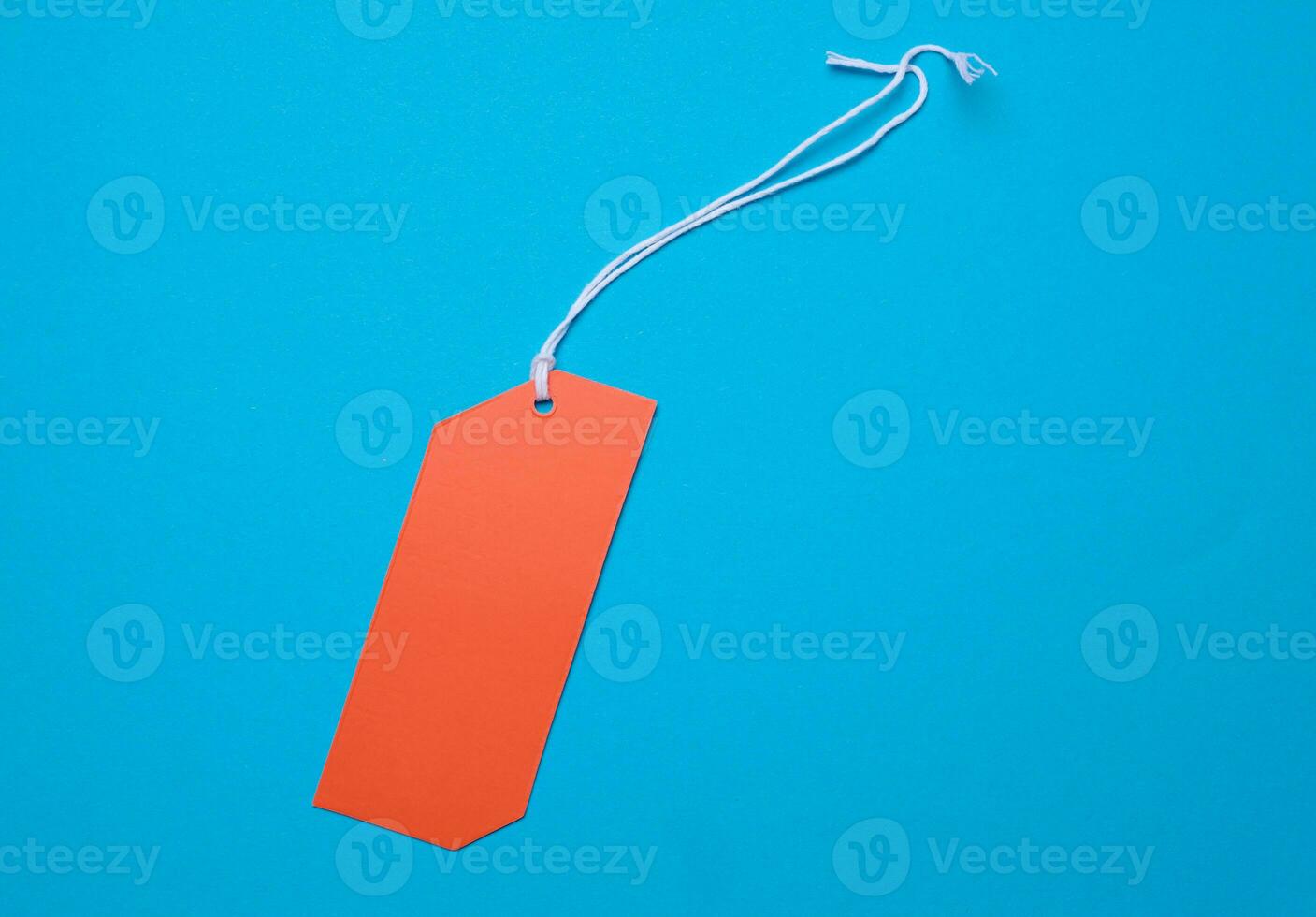 Orange price tag with a white string for clothing and merchandise on a blue background photo