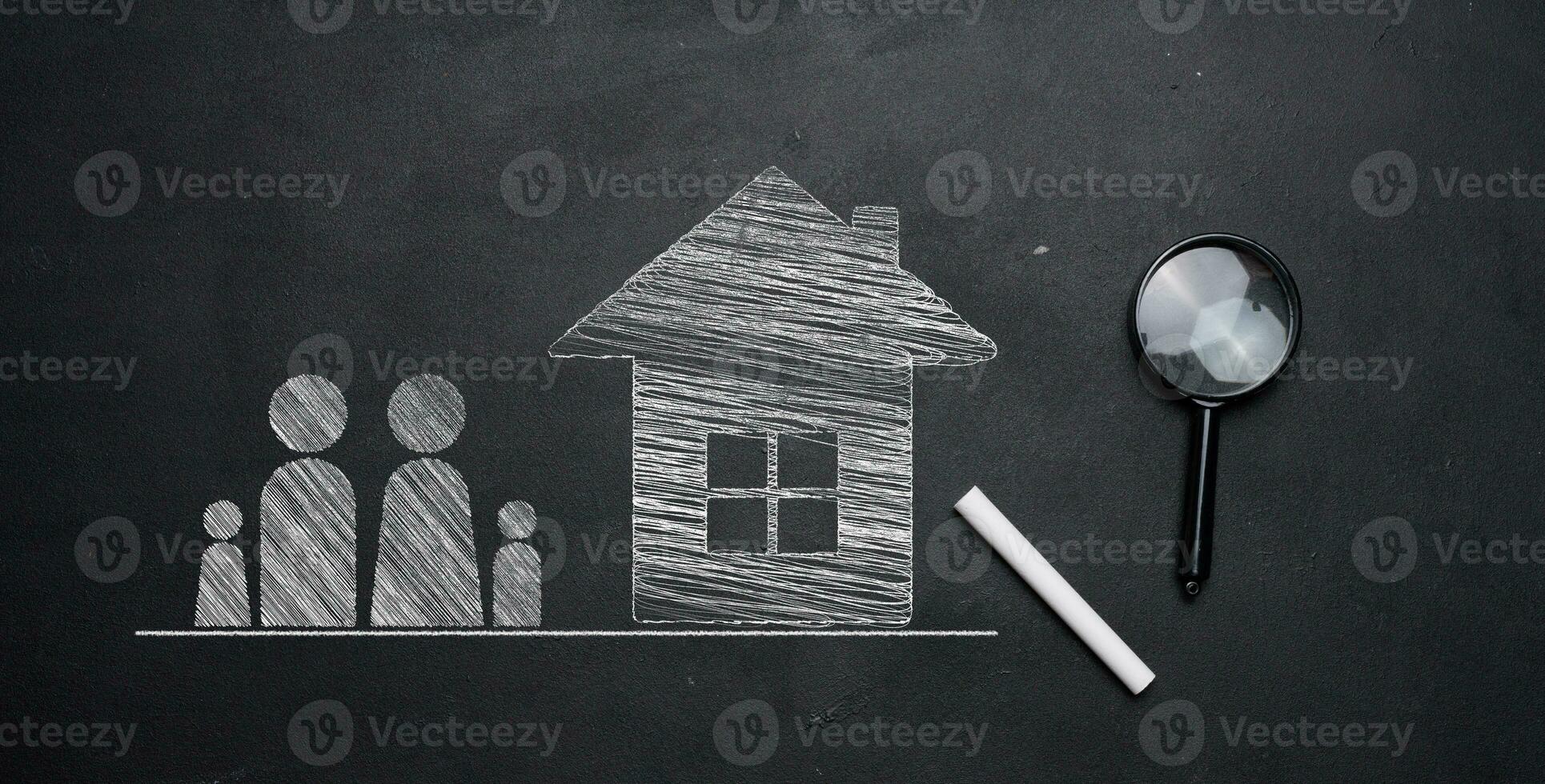 Chalk-drawn family figures and a house on a black chalkboard, with a magnifying glass and chalk nearby. Concept of affordable mortgage or rent for a young family. photo