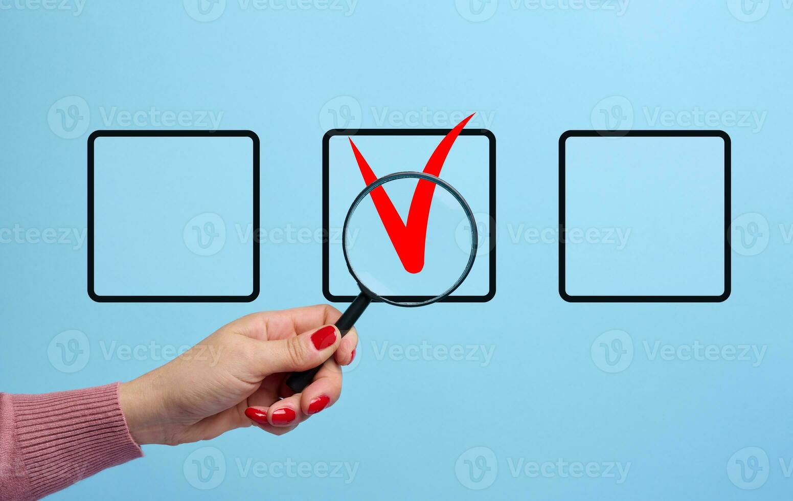 A woman's hand holds a magnifying glass and a marker with a red checkmark. Quality control concept, approval and rejection. Voting for photo