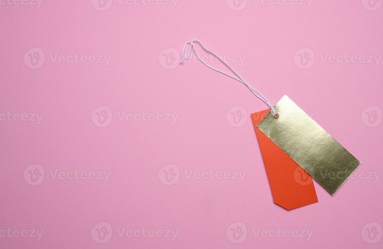 Price tag with a white string for clothing and merchandise on a pink background. Copy space photo