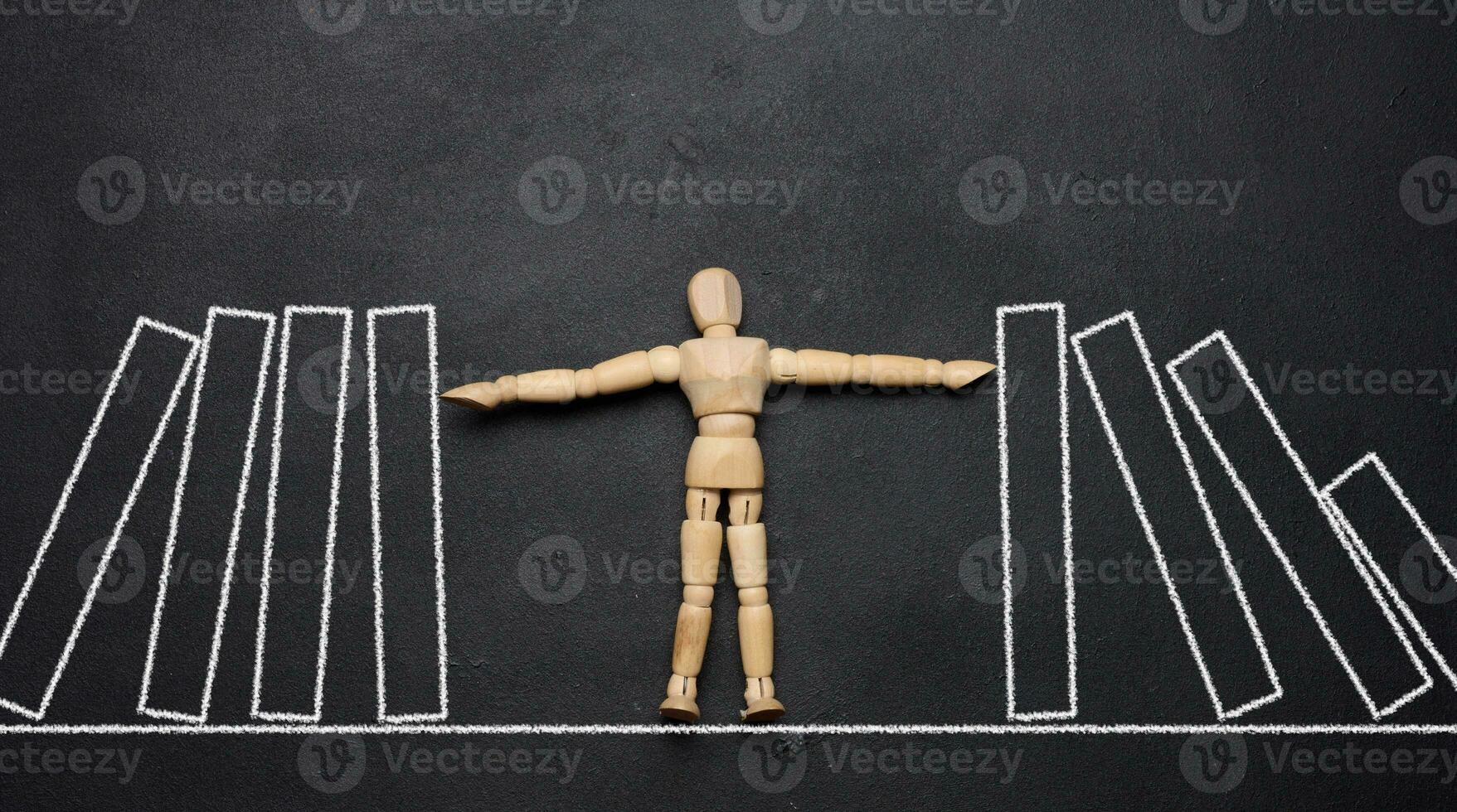 Wooden puppet toy holding a falling domino, representing the concept of a strong personality photo