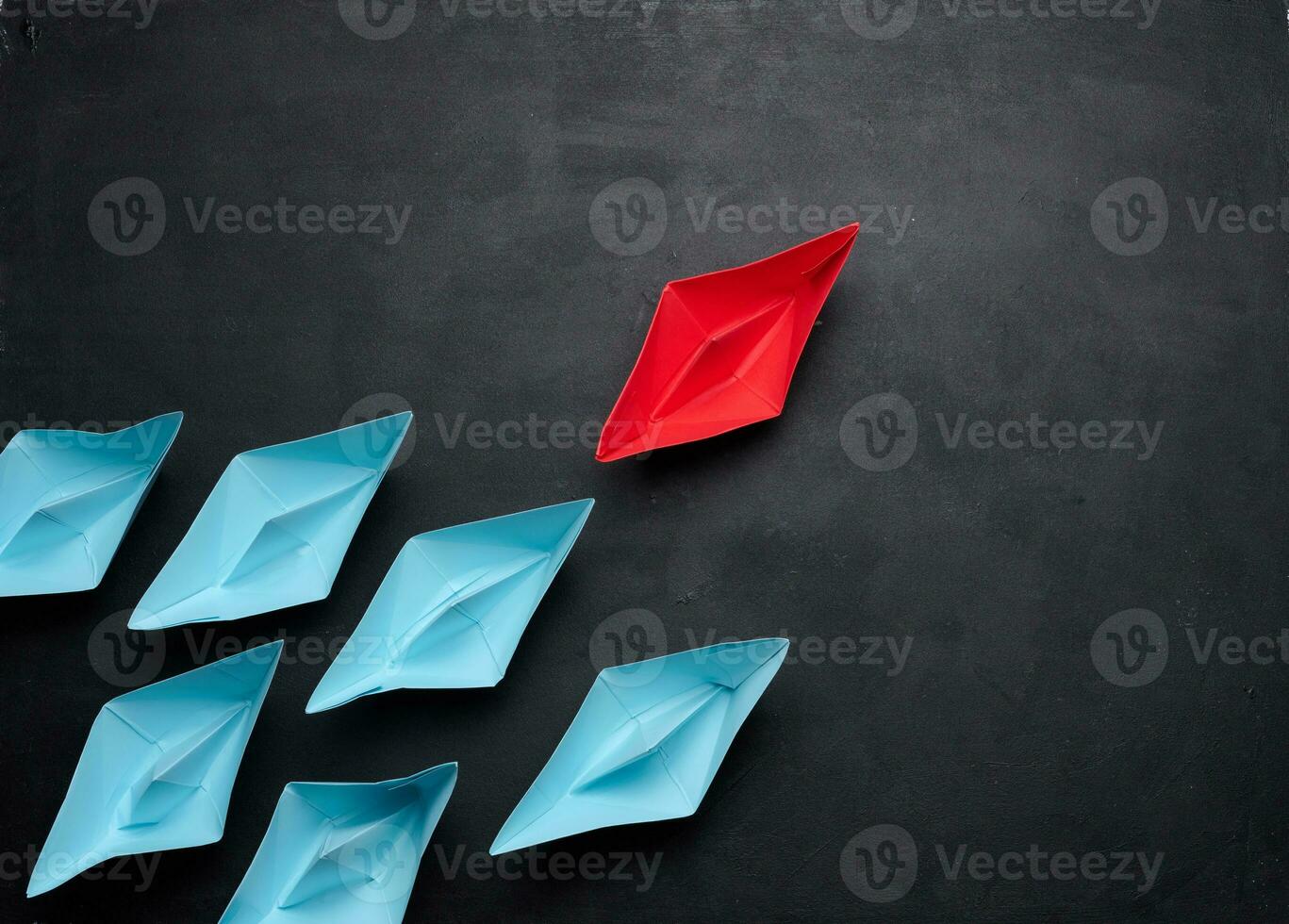 Group of paper boats on a black background.Concept of a strong leader in a team, manipulation of the masses, following new perspectives photo