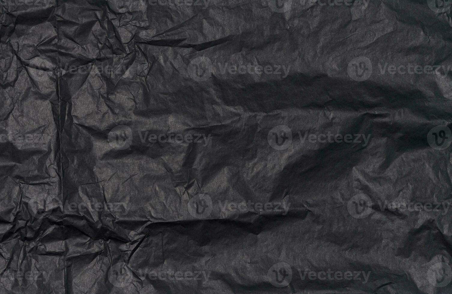 Crumpled sheet of black parchment paper, abstract background photo