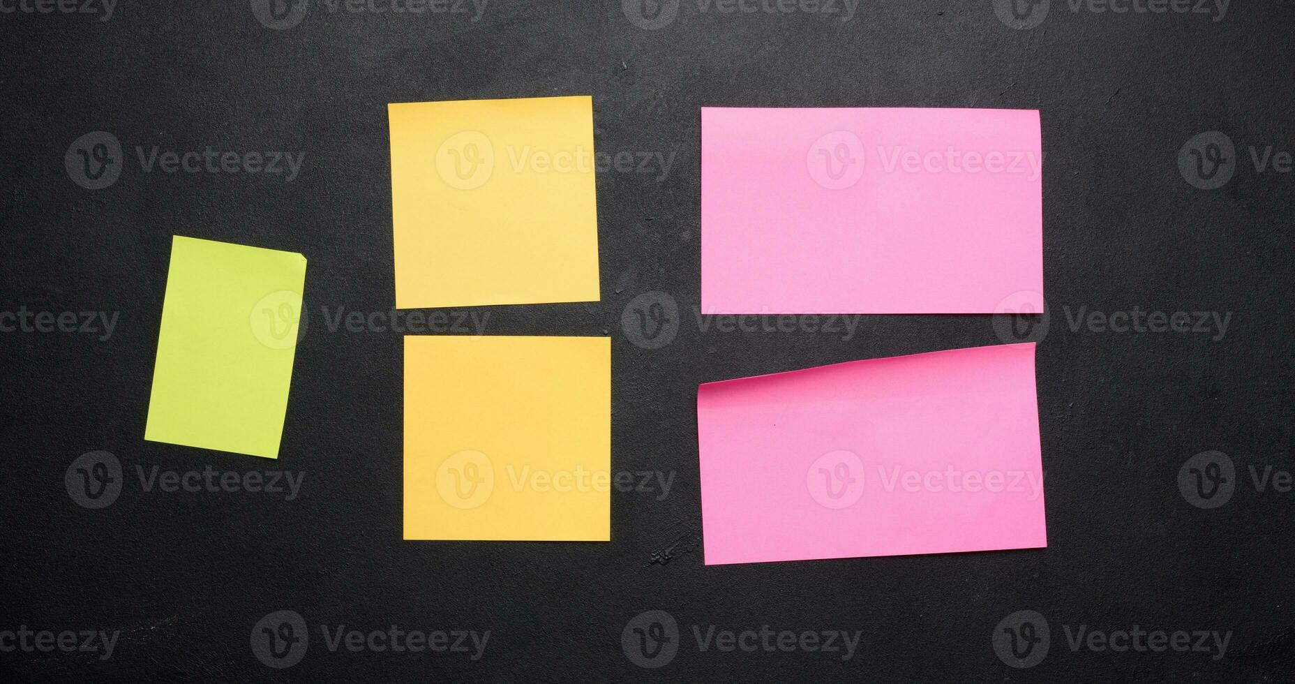 Multicolored paper stickers on a black chalkboard, space for notes and labels photo