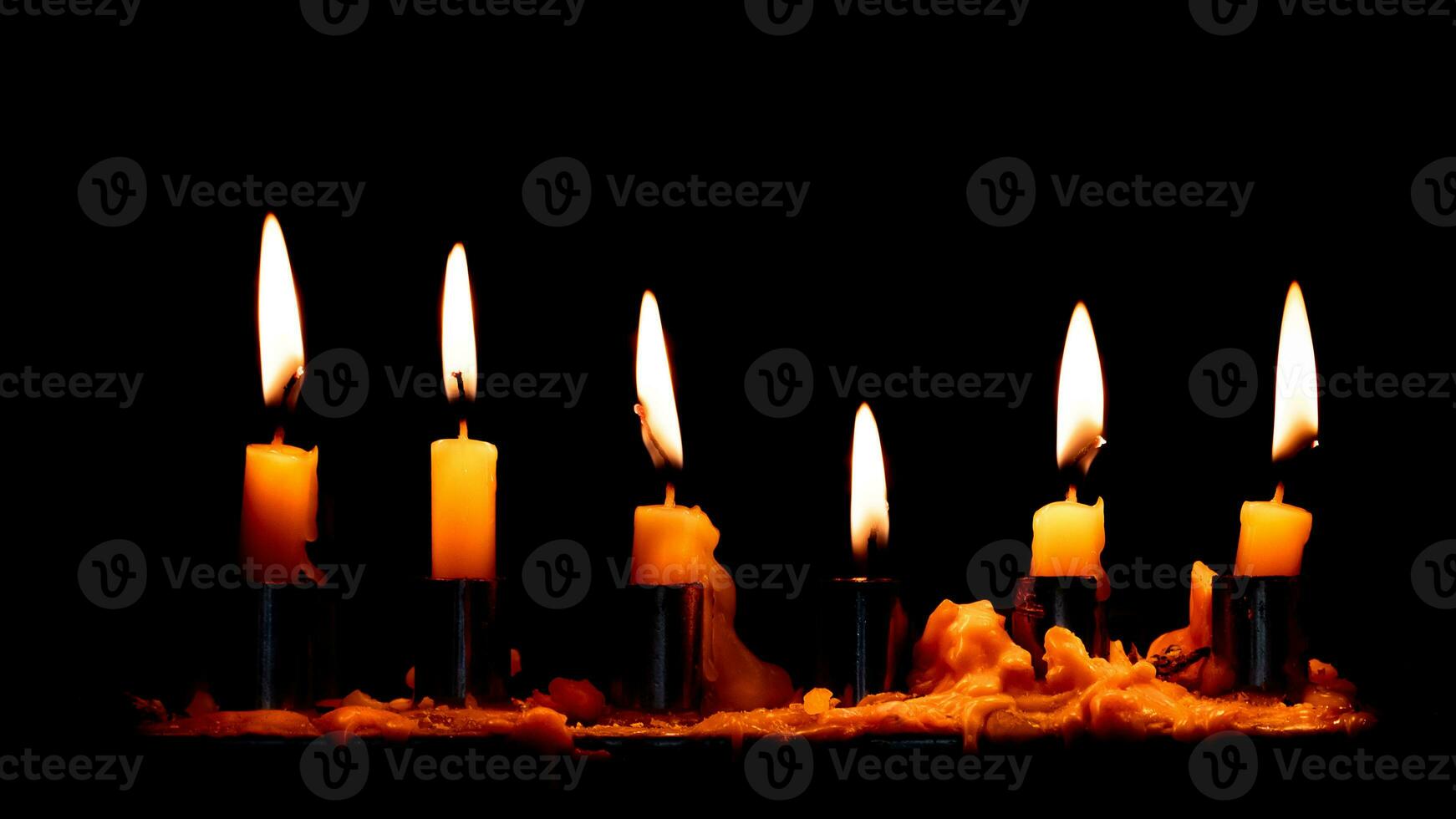 Group of burning candles on dark candle holder and black background, space for text on top. Buddhism Memory day photo