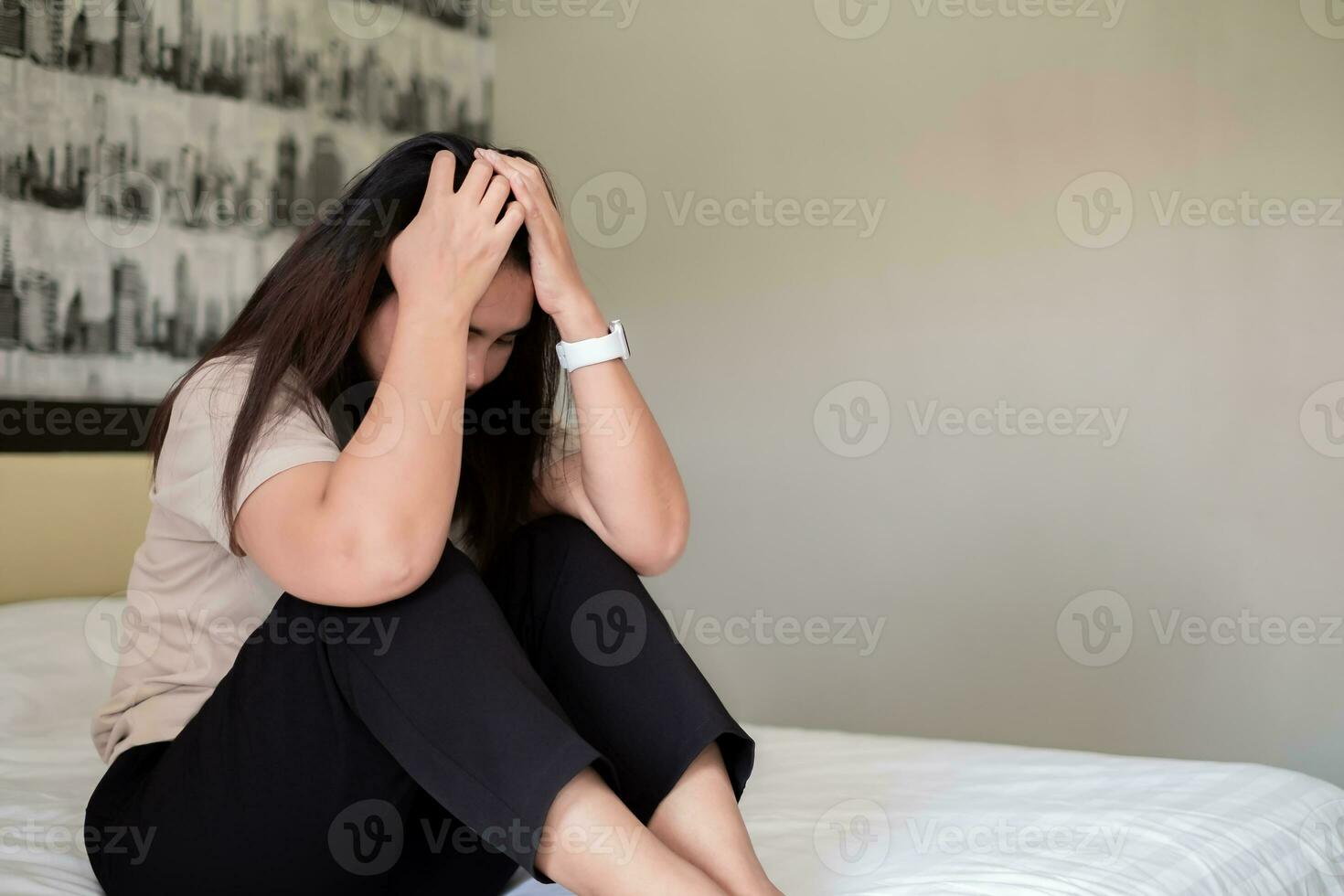 Sad depressed asia woman suffering on the white bed, she is sitting in bed and touching her forehead, sleep disorder and stress concept photo